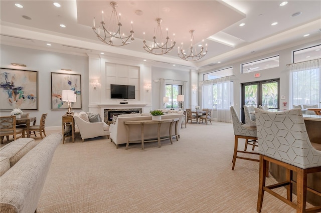 living room featuring an inviting chandelier, light colored carpet, a tray ceiling, and a wealth of natural light