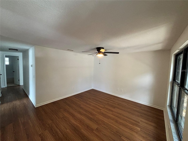 spare room featuring ceiling fan, dark wood-type flooring, and a textured ceiling