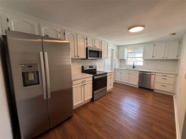 kitchen featuring white cabinets, a textured ceiling, appliances with stainless steel finishes, and dark hardwood / wood-style flooring