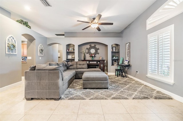 tiled living room featuring plenty of natural light, built in features, and ceiling fan