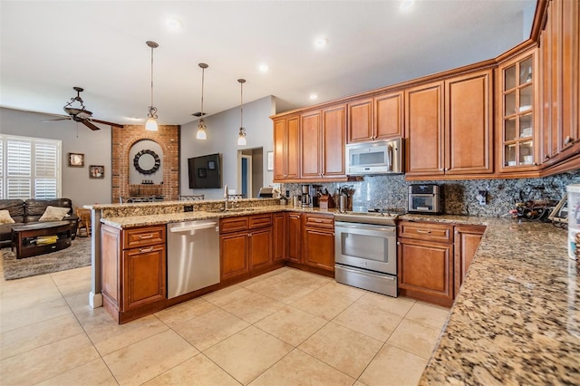 kitchen featuring tasteful backsplash, kitchen peninsula, ceiling fan, stainless steel appliances, and brick wall