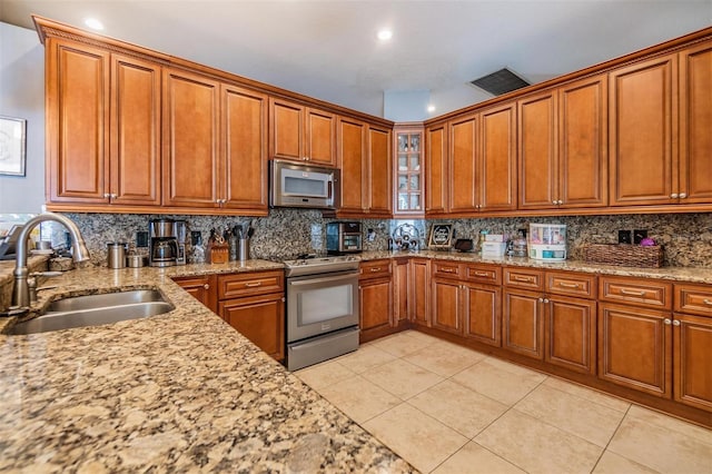 kitchen with stainless steel appliances, decorative backsplash, sink, light stone countertops, and light tile patterned floors