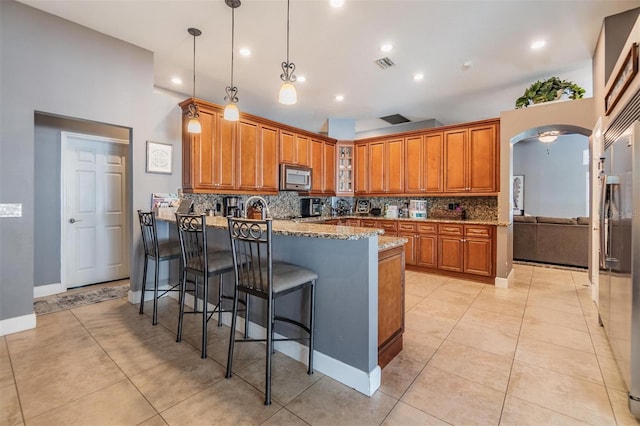 kitchen with light stone countertops, stainless steel appliances, backsplash, and light tile patterned floors