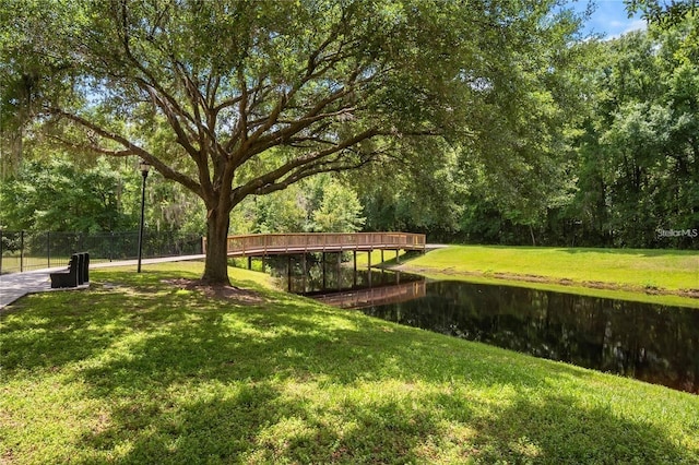 surrounding community with a water view and a lawn