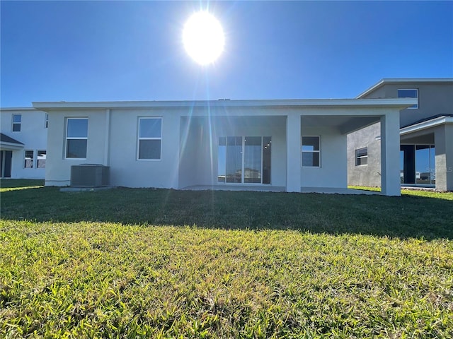 rear view of house with a lawn and central AC