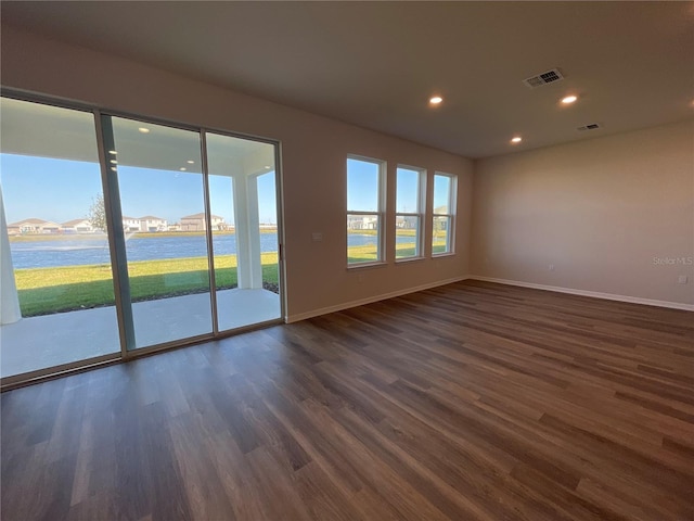 spare room with a water view, plenty of natural light, and dark hardwood / wood-style flooring