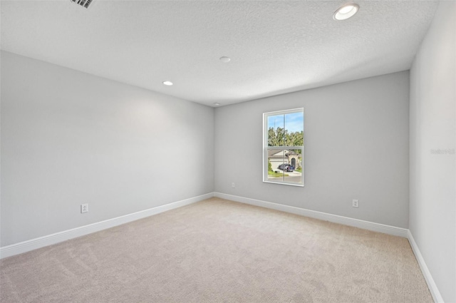 unfurnished room featuring light carpet and a textured ceiling