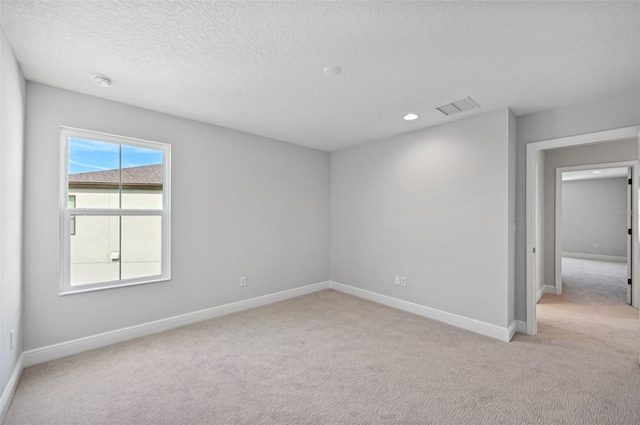 carpeted empty room with a textured ceiling