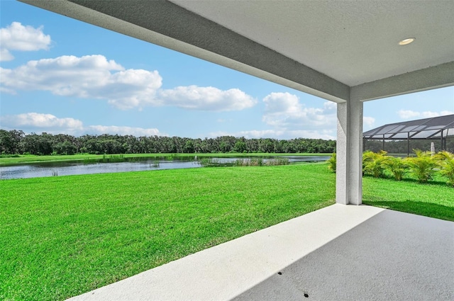 view of yard with a water view, glass enclosure, and a patio