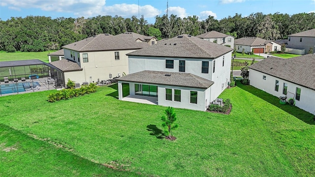 back of property featuring a lawn, a patio, and glass enclosure