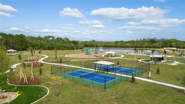 view of tennis court featuring a water view, a yard, and a playground