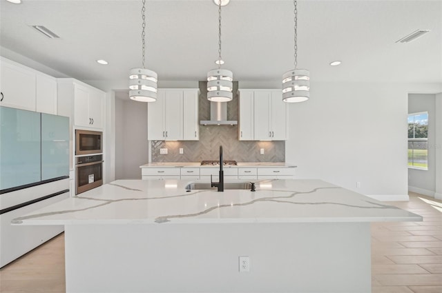 kitchen featuring sink, white cabinetry, appliances with stainless steel finishes, a large island, and light stone countertops