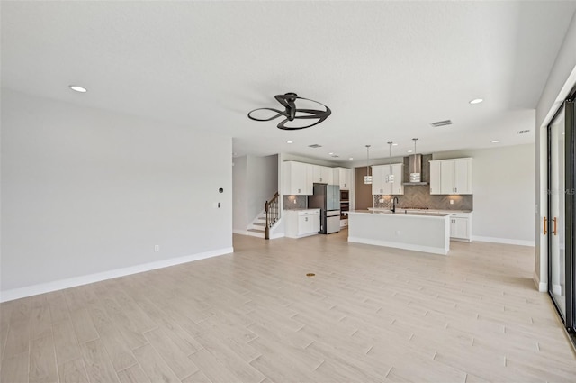 unfurnished living room with sink, light hardwood / wood-style floors, and ceiling fan