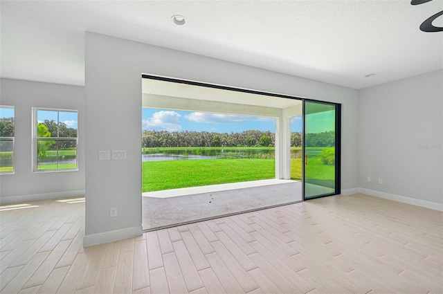 unfurnished room featuring light hardwood / wood-style flooring, a textured ceiling, and a water view