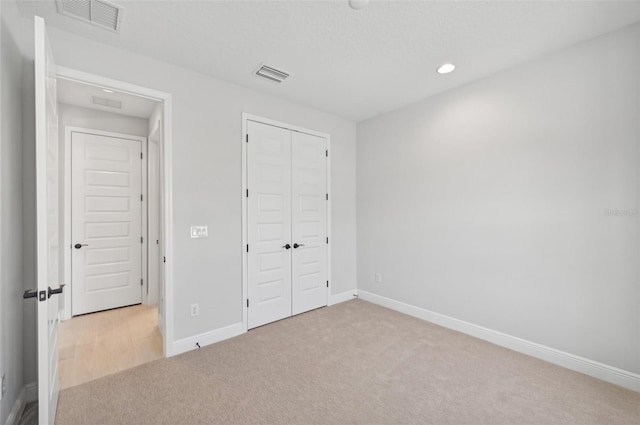 unfurnished bedroom with light colored carpet and a closet