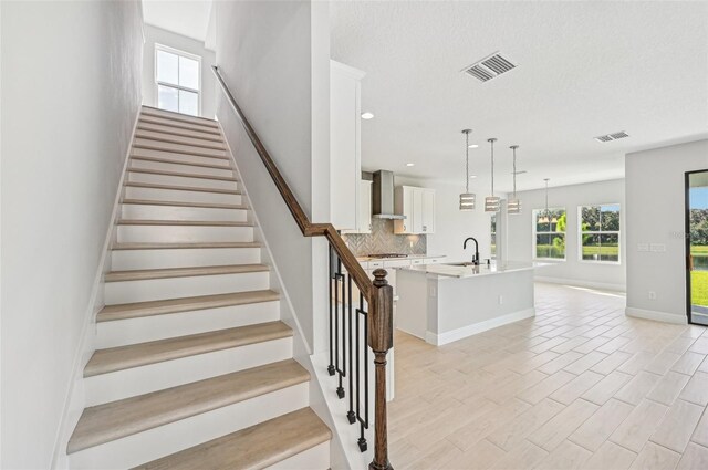 stairs with sink, hardwood / wood-style floors, and a textured ceiling