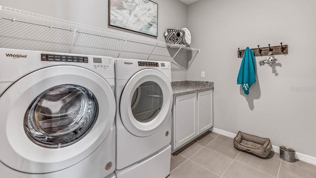 laundry room featuring cabinets, washing machine and clothes dryer, and light tile patterned flooring