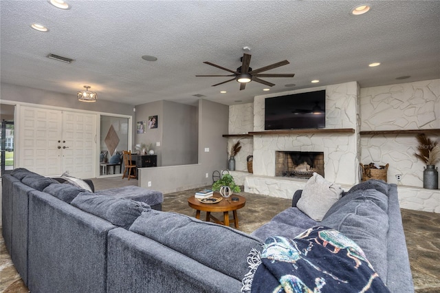 living room with a fireplace, a textured ceiling, and ceiling fan