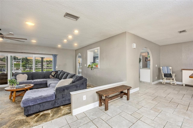 living room with ceiling fan and a textured ceiling