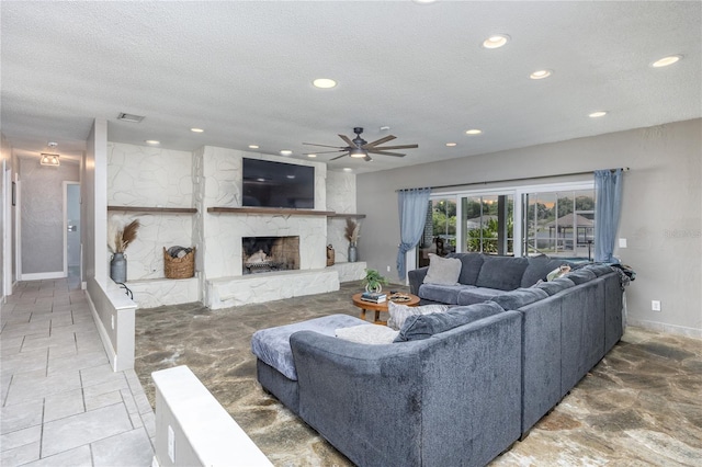 living room featuring a textured ceiling, ceiling fan, and a fireplace