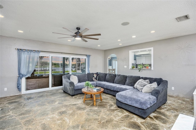 living room with ceiling fan and a textured ceiling