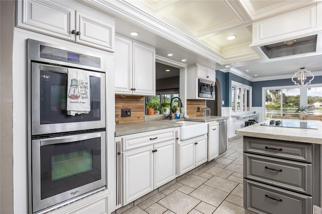 kitchen featuring appliances with stainless steel finishes, coffered ceiling, crown molding, sink, and white cabinetry