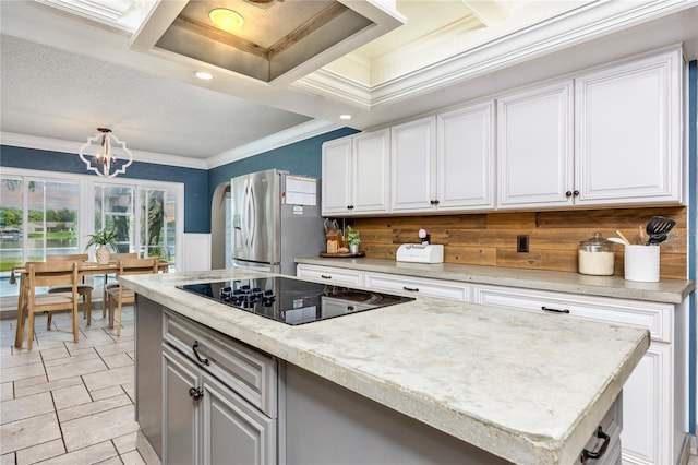 kitchen featuring a center island, an inviting chandelier, stainless steel fridge, black electric cooktop, and white cabinets