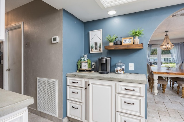 kitchen with light tile patterned floors, white cabinets, and decorative light fixtures