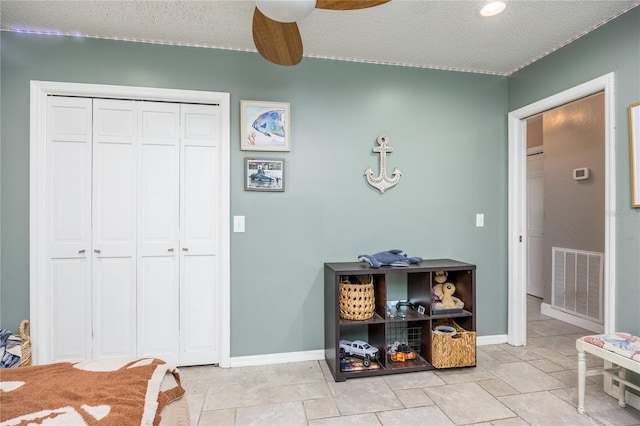 interior space with a textured ceiling and ceiling fan