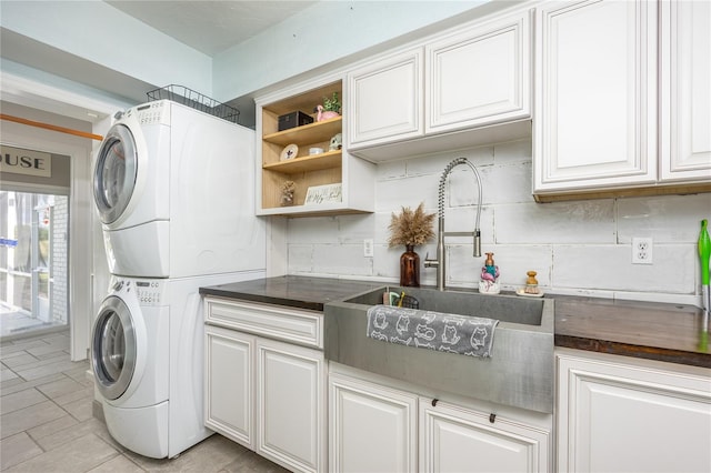 washroom featuring sink, cabinets, and stacked washer and dryer