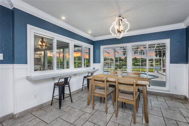 dining space featuring a chandelier, a textured ceiling, and ornamental molding