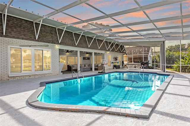 pool at dusk featuring glass enclosure, ceiling fan, an outdoor hangout area, and a patio