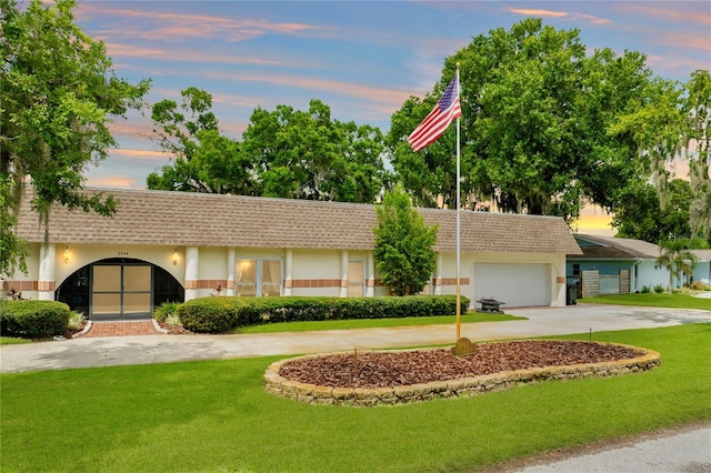 single story home with a garage and a lawn