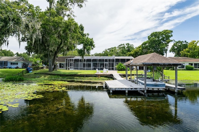 view of dock with a water view, boat lift, and a lawn