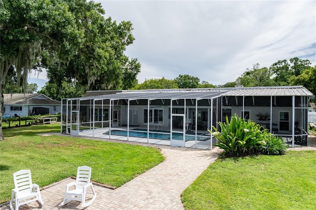 rear view of house with a patio, a lawn, glass enclosure, and an outdoor pool