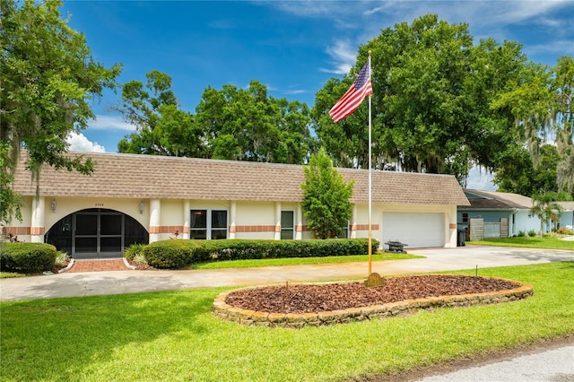 ranch-style home with driveway, an attached garage, roof with shingles, and a front yard