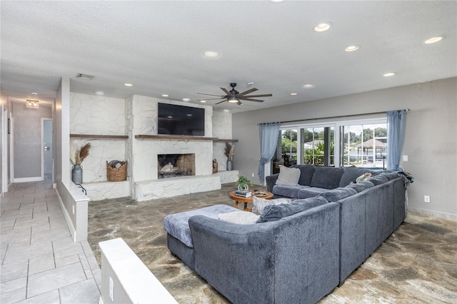 living area featuring a textured ceiling, recessed lighting, visible vents, a high end fireplace, and stone finish flooring