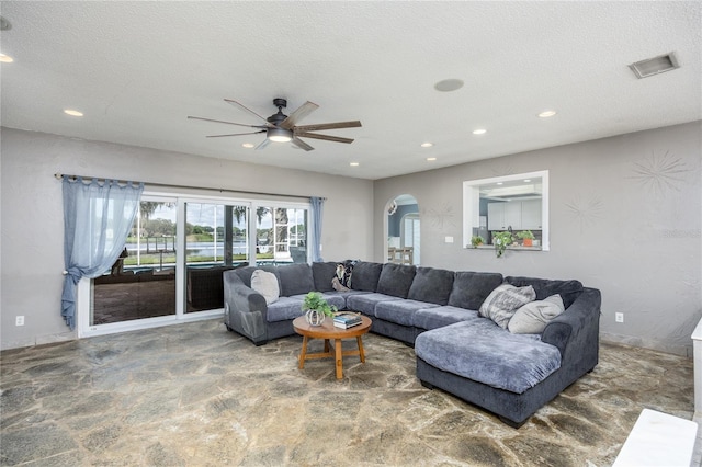 living area with arched walkways, visible vents, a textured ceiling, and recessed lighting