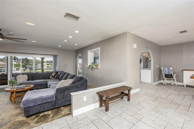 living room featuring arched walkways, visible vents, and a textured ceiling