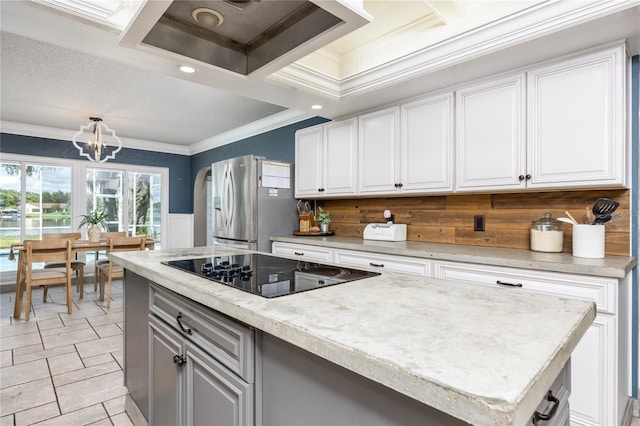 kitchen with arched walkways, crown molding, white cabinetry, stainless steel fridge, and black electric cooktop