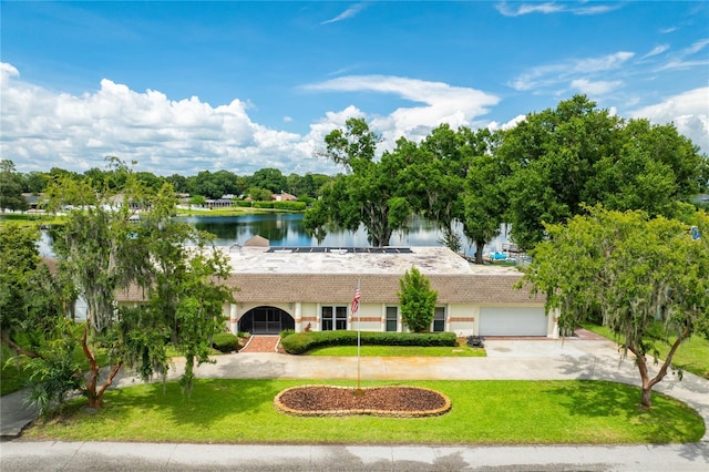 view of front of home with driveway, a front lawn, and a water view