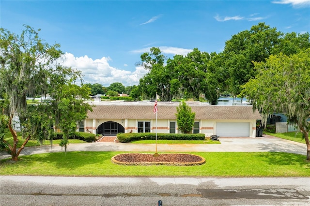 single story home featuring an attached garage, curved driveway, a front lawn, and a tiled roof