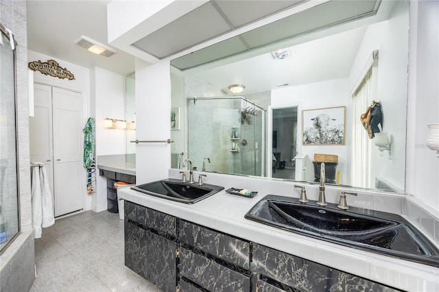 full bath featuring double vanity, a shower stall, visible vents, and a sink