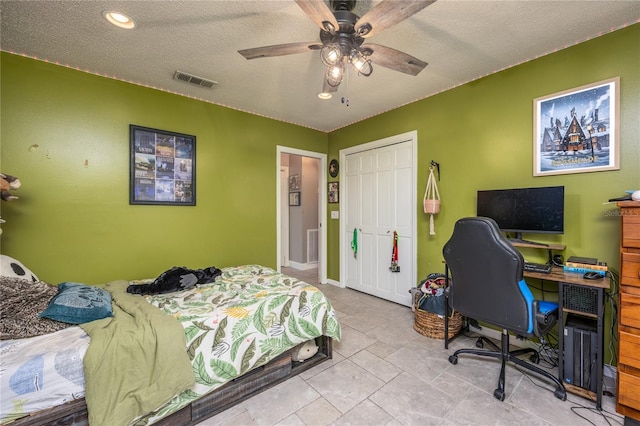 bedroom with a textured ceiling, ceiling fan, a closet, and visible vents