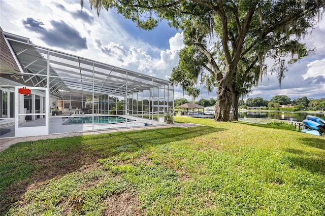 view of yard featuring glass enclosure, a patio, a water view, and an outdoor pool