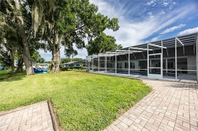 view of yard with glass enclosure, a patio area, and a pool