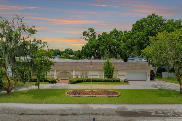 ranch-style home with driveway, a yard, and a tile roof