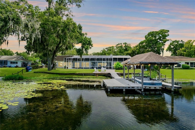 dock area featuring a water view, boat lift, and a lawn