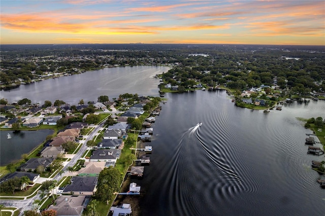 aerial view at dusk featuring a water view and a residential view