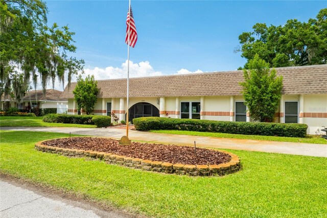 single story home featuring driveway, roof with shingles, mansard roof, and a front yard